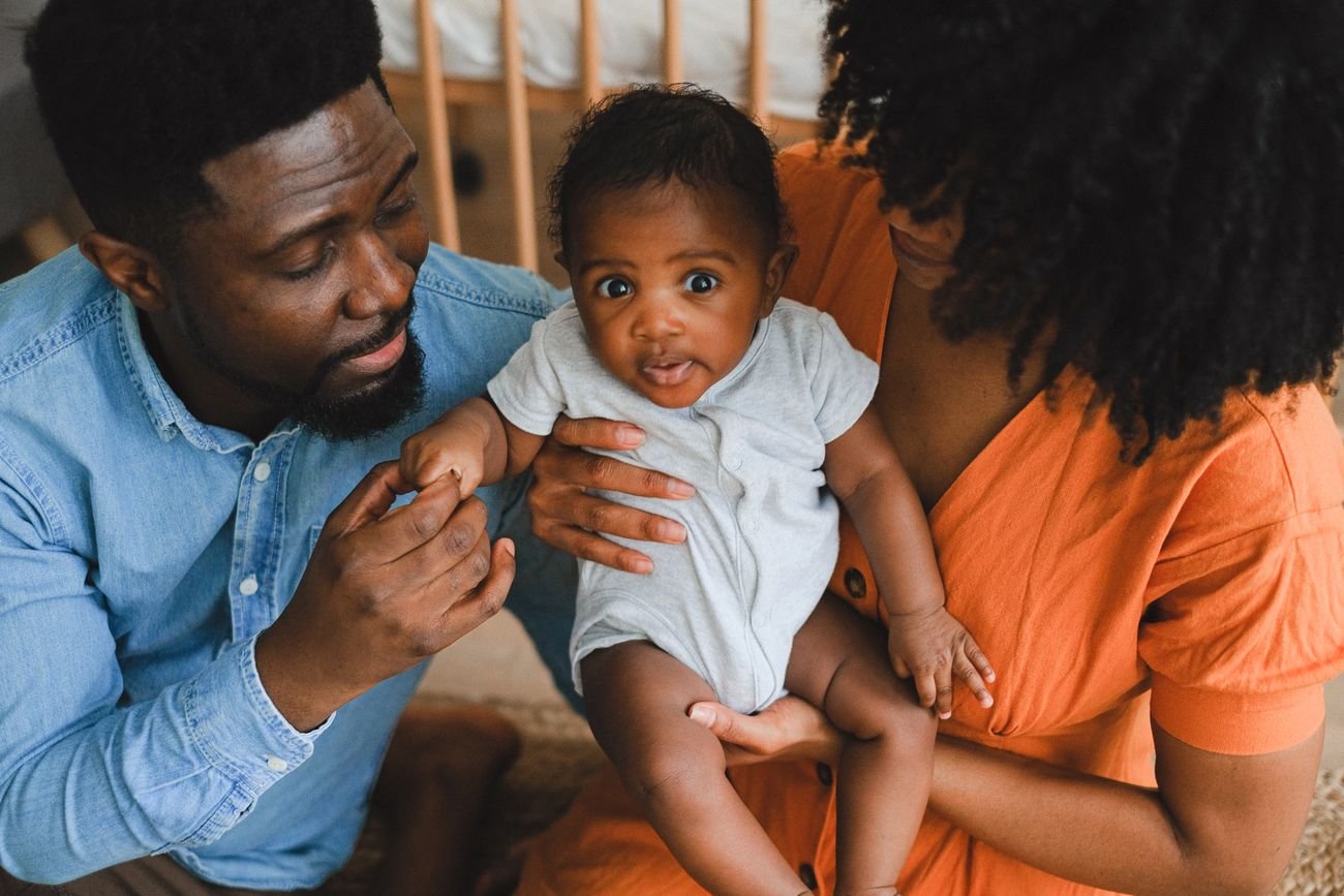 Un bébé tenu assis par ses parents